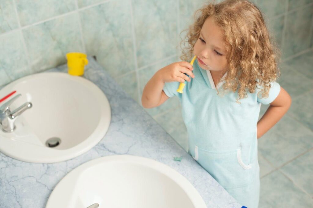 Bild på en liten flicka som borstar tänderna med fluortandkräm